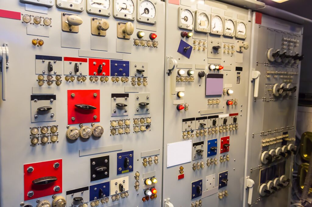 Large electrical control panel with meters, switches, and indicator lights on an industrial switchboard.