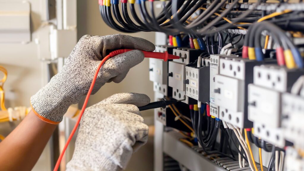 Technician testing an electrical control panel with a multimeter